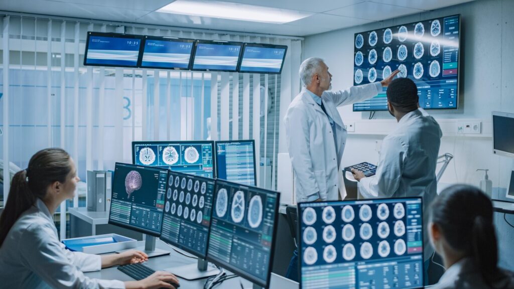 Clinical team reviewing medical scans across several monitors in an imaging room