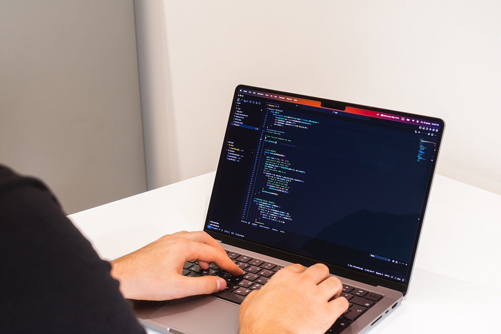 Hands typing on a laptop showing lines of code