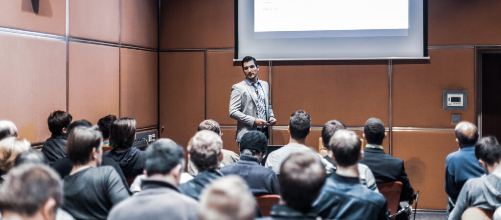 The conference talk Speaker giving a talk to a full audience in a conference hall
