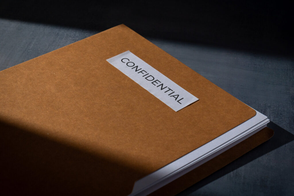 Brown folder labeled confidential lying on a dark desk
