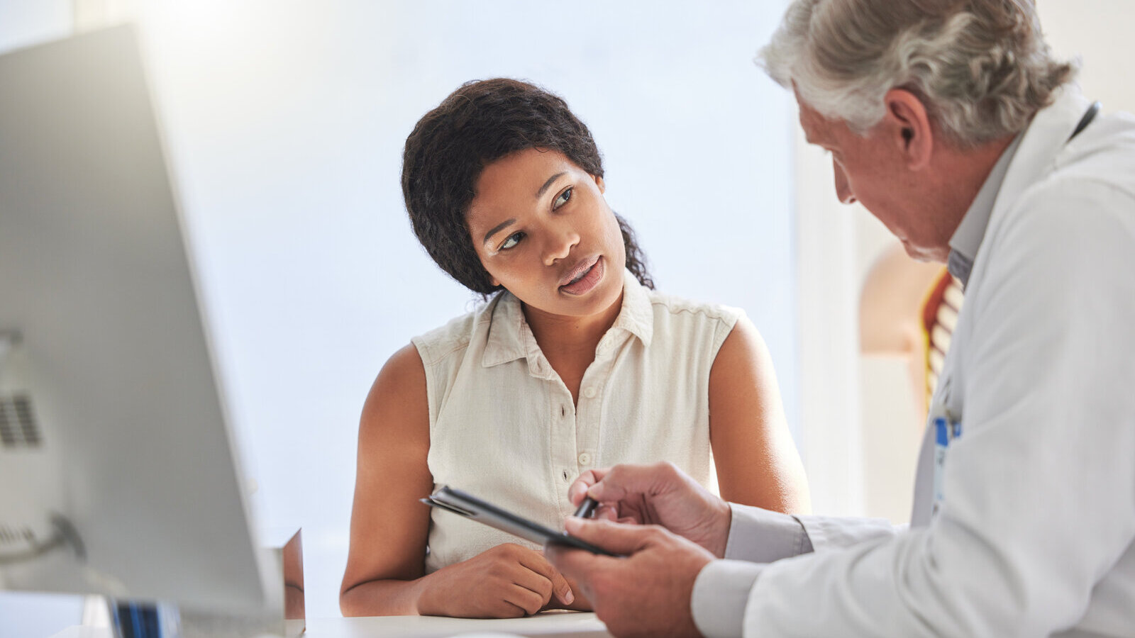 Doctor going over results on a tablet with a patient at a desk