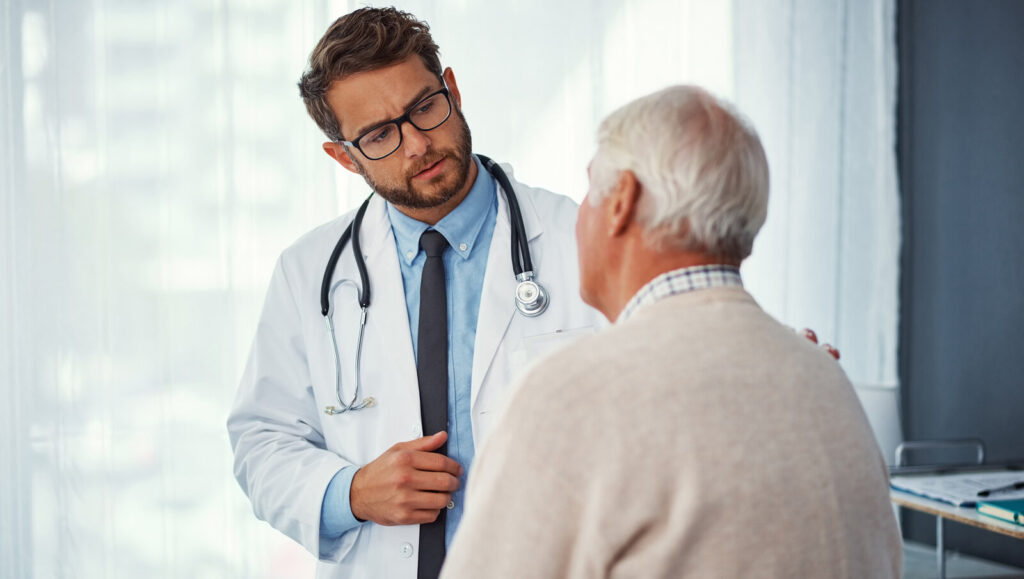 Doctor in a white coat talking with an older man in a clinic