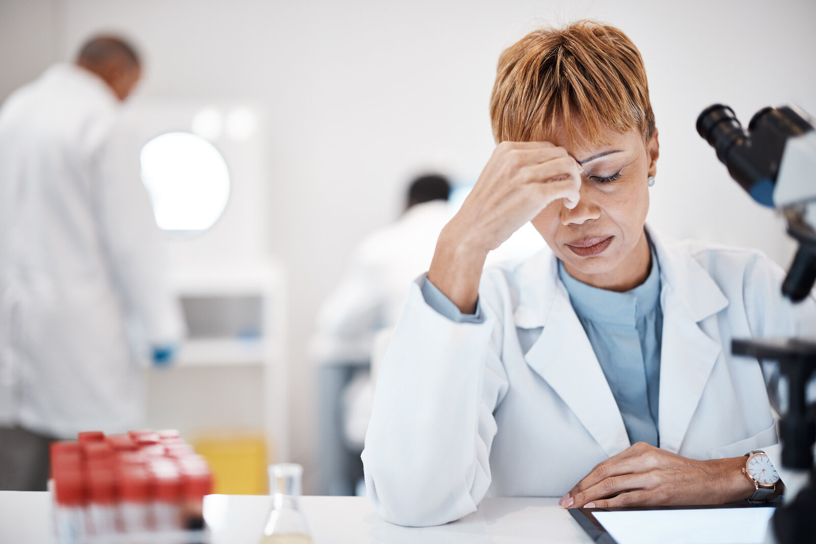 Scientist at a lab bench holding her head in frustration