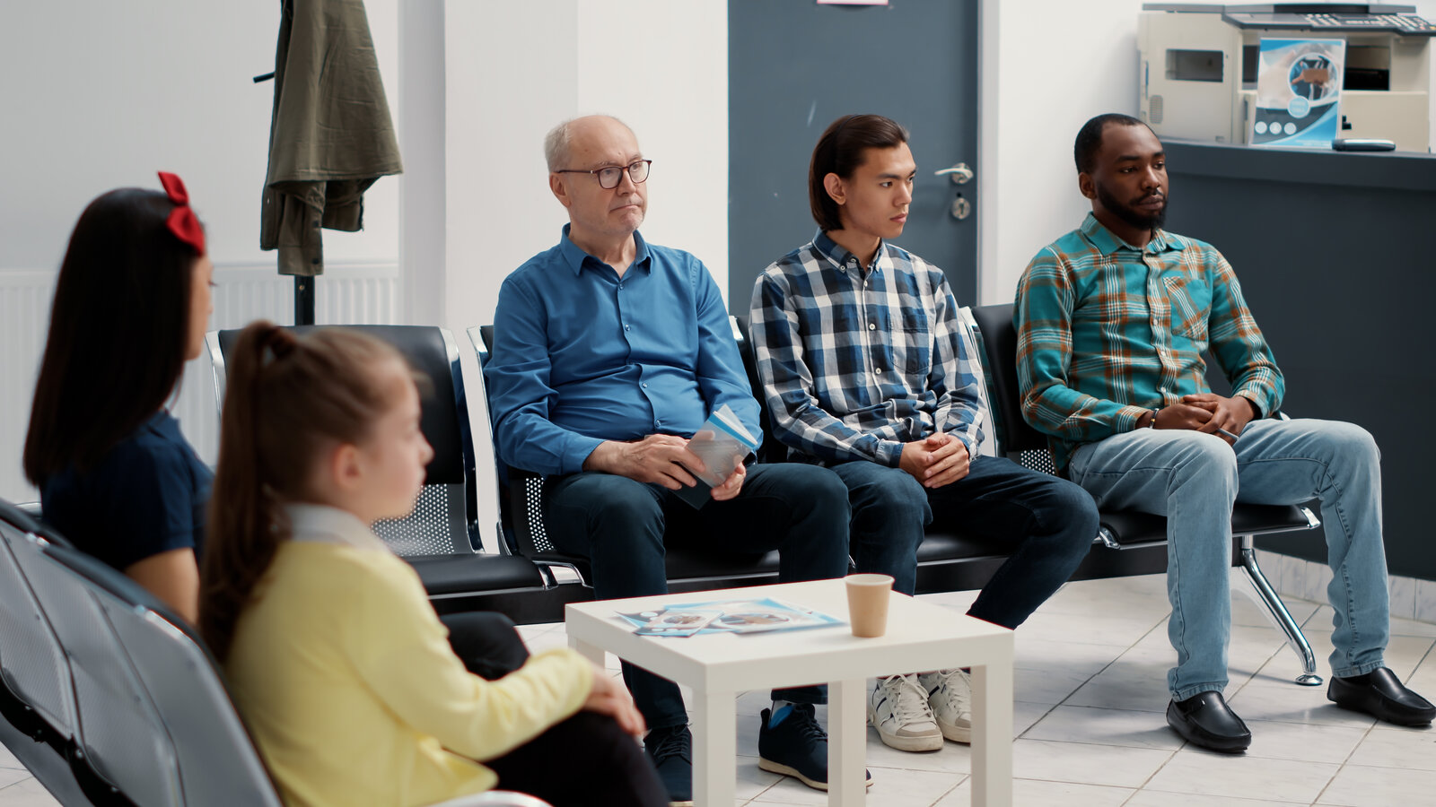 Patients of different ages and backgrounds sitting in a hospital waiting room
