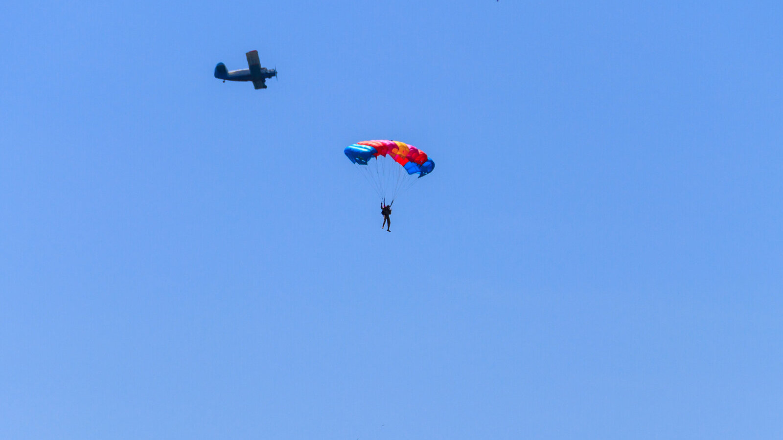 Small airplane and a parachutist against a clear blue sky