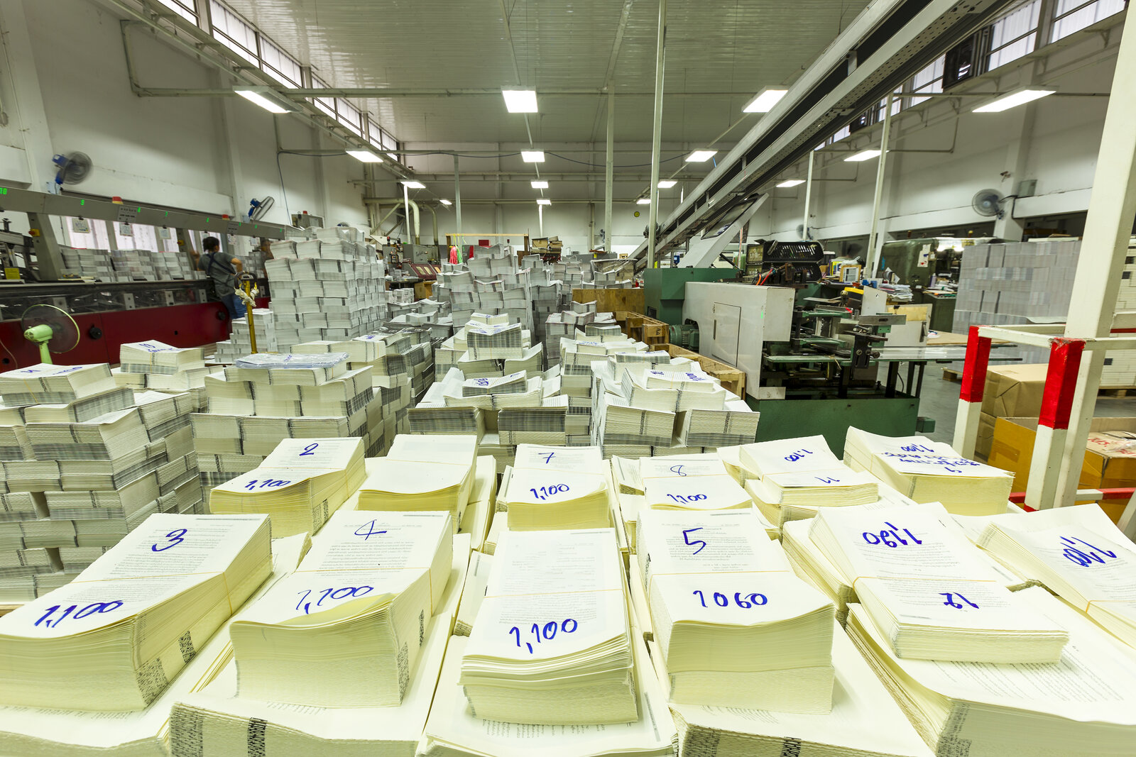 Printing plant floor stacked with numbered bundles of paper