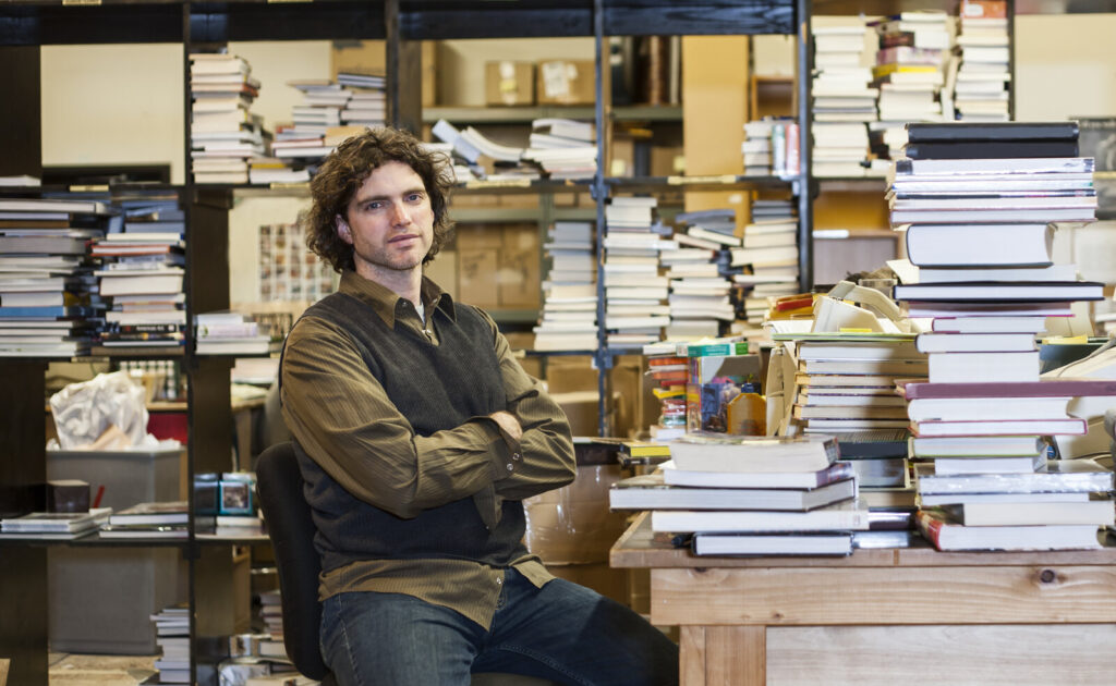 More and more papers Researcher sitting among tall piles of books and journals