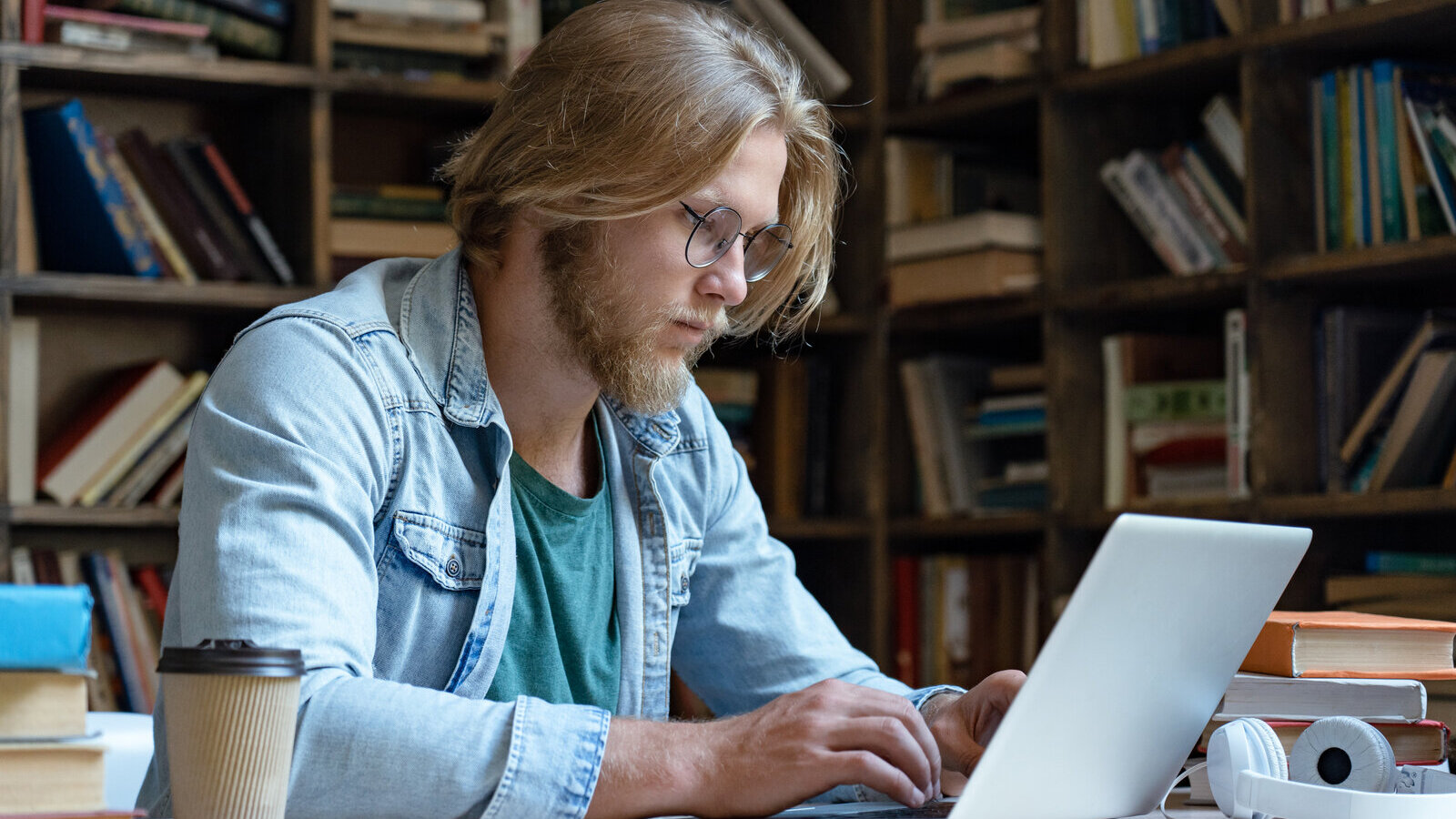 Researcher typing on a laptop at a desk in front of bookshelves