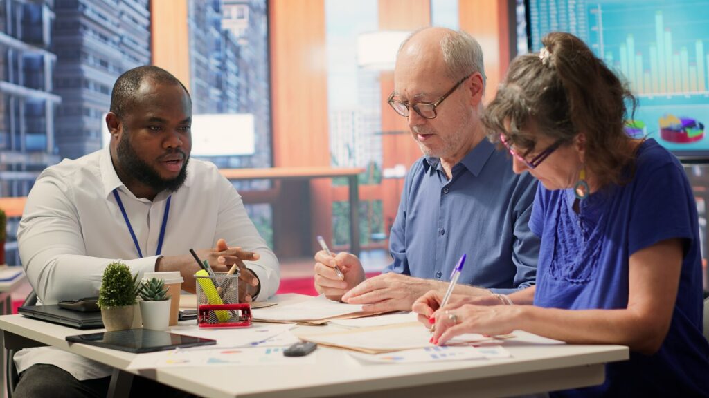 Three colleagues at a table marking up printed documents with pens