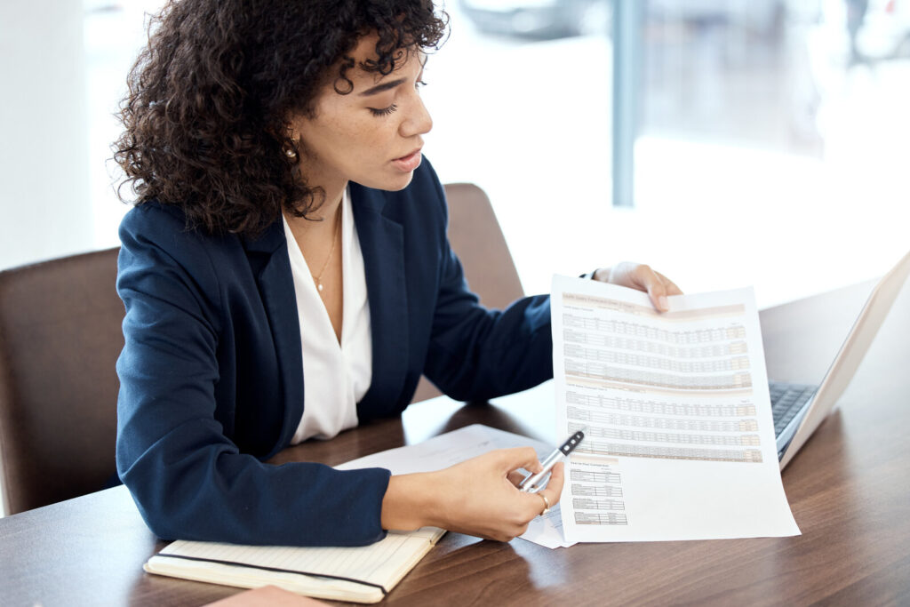Professional at a desk reviewing a printed document with a pen