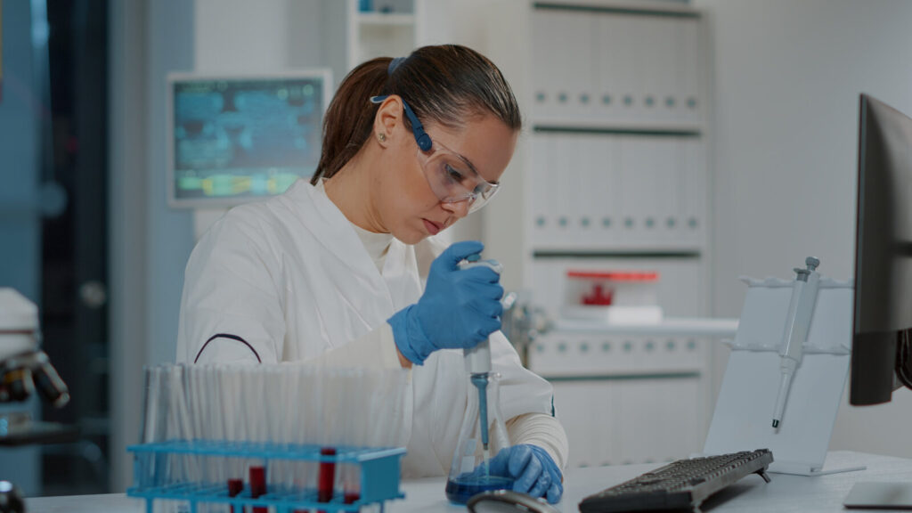 Measuring in the lab Scientist in safety glasses pipetting samples at a laboratory bench