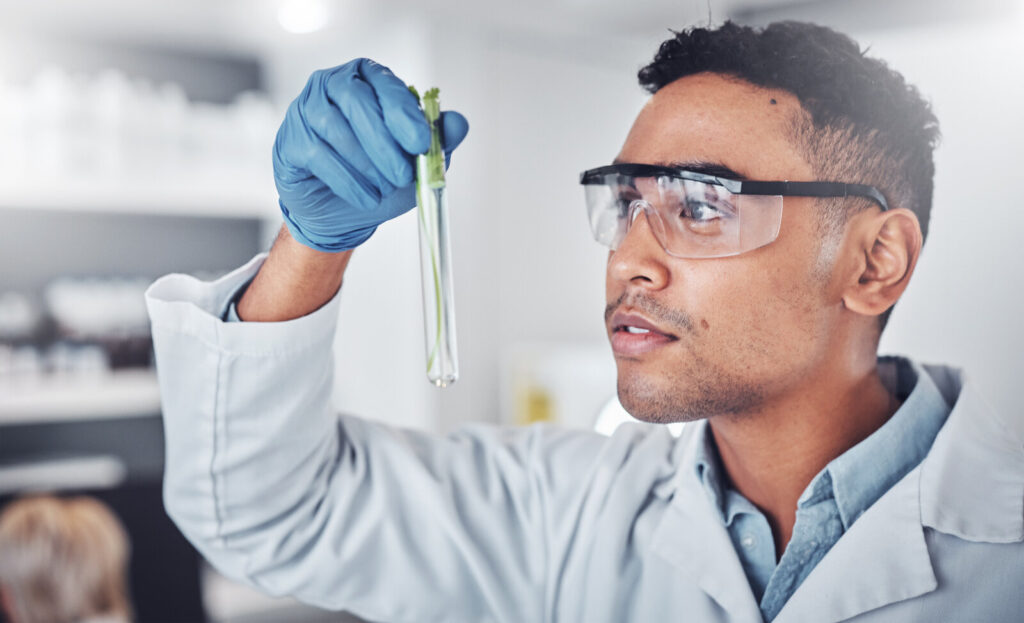 Scientist in safety glasses examining a test tube in a laboratory