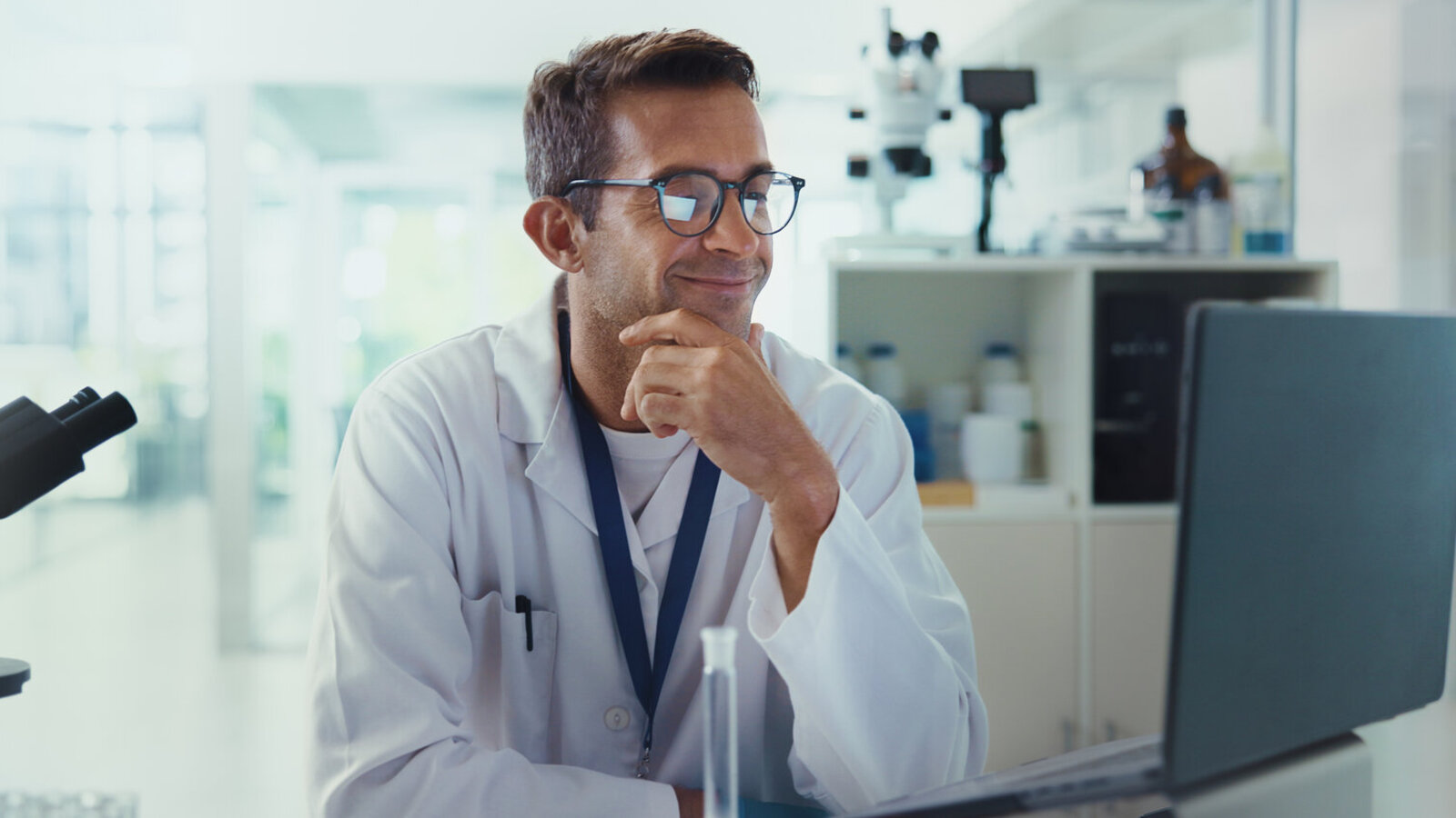 Scientist in a lab coat sitting at a desk, deep in thought