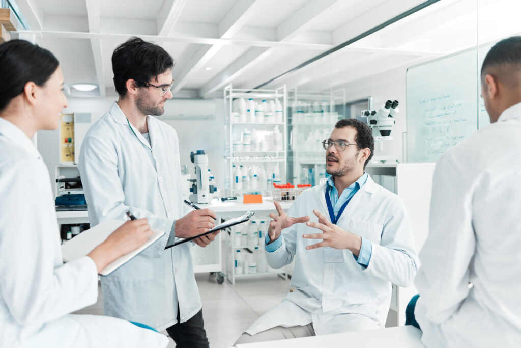 Group of scientists in lab coats talking over notes in a laboratory