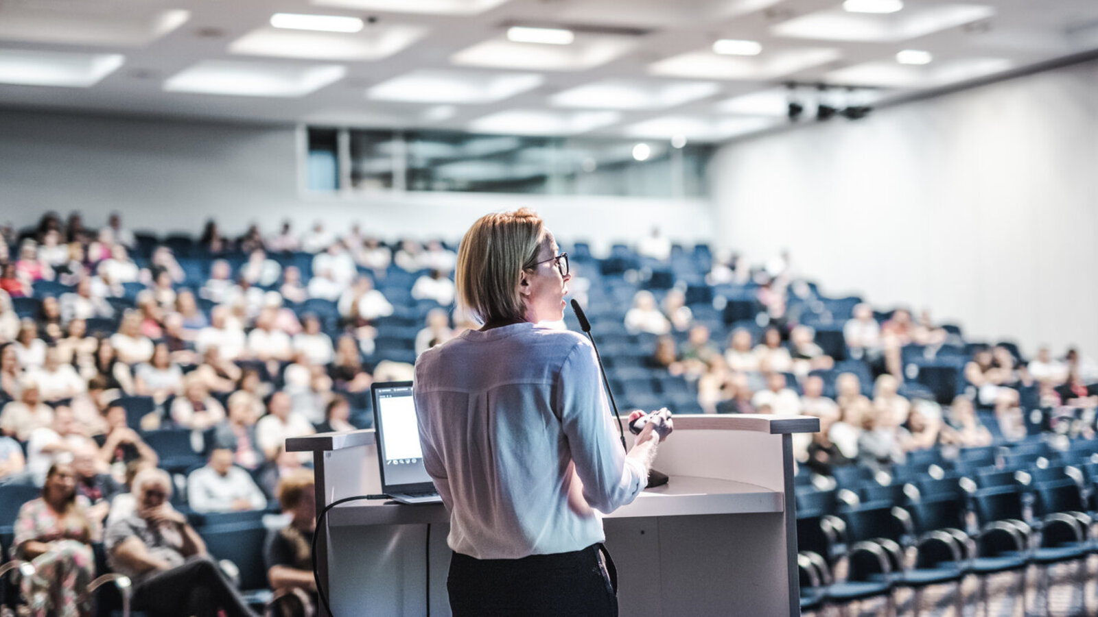 Speaker at a podium addressing a large conference audience