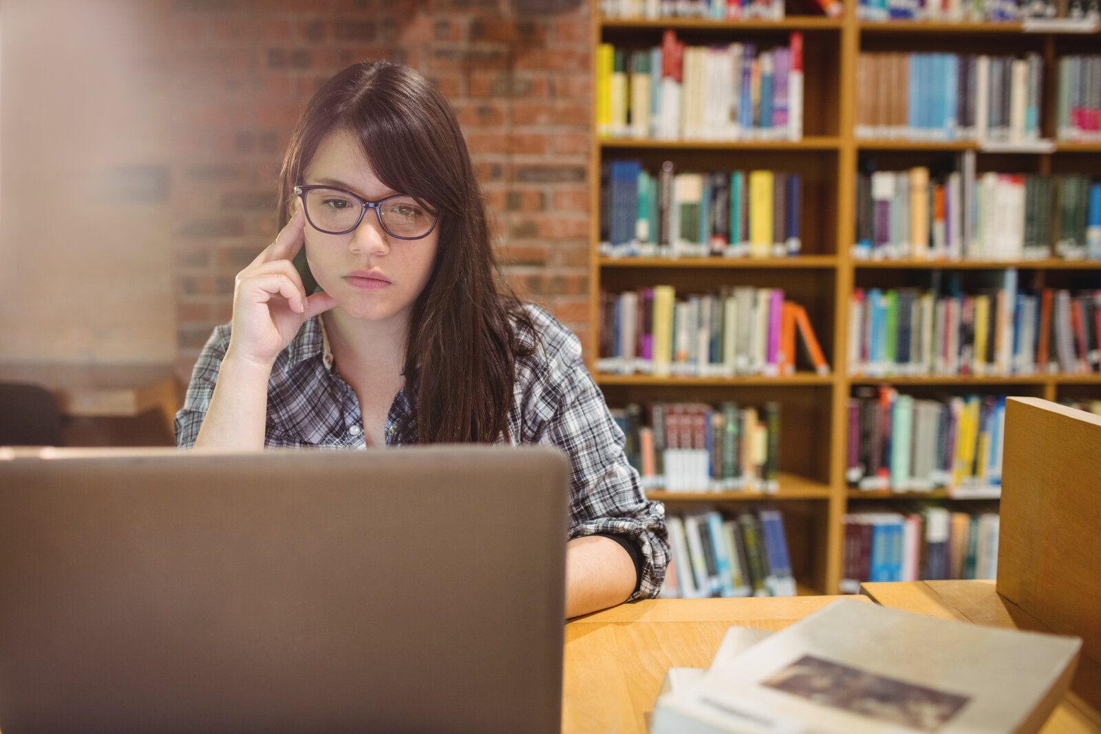 Student in a library looking closely at a laptop screen