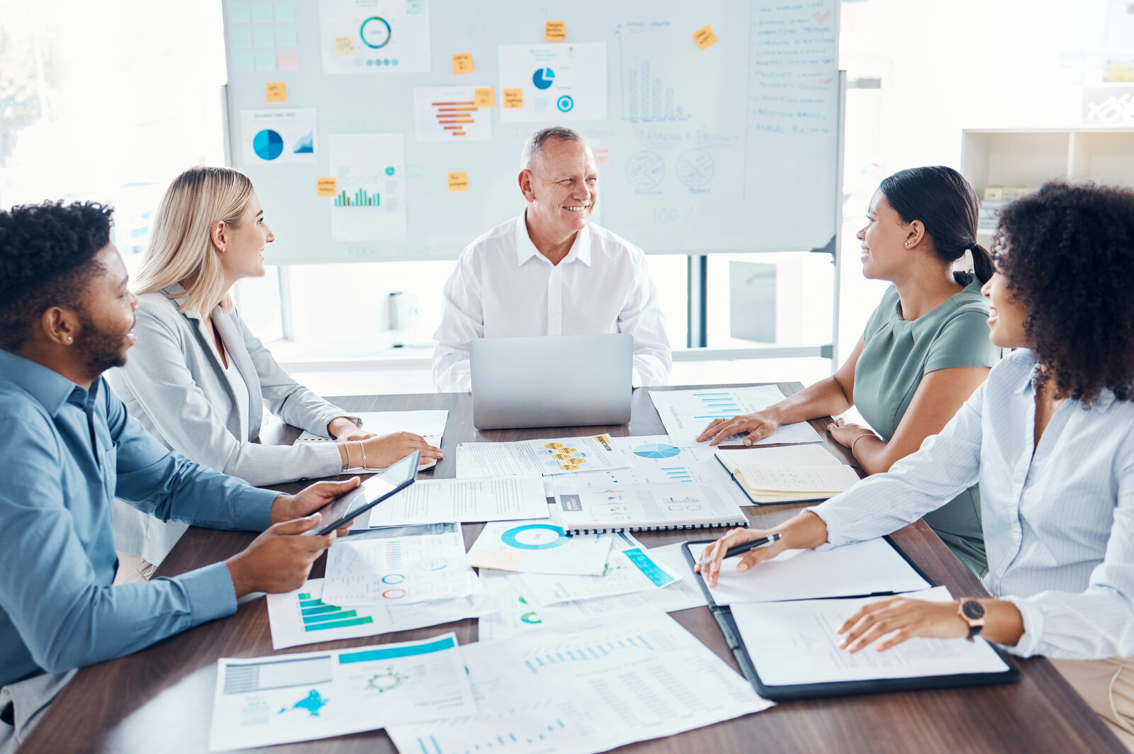 Team of researchers around a table covered in charts and data printouts