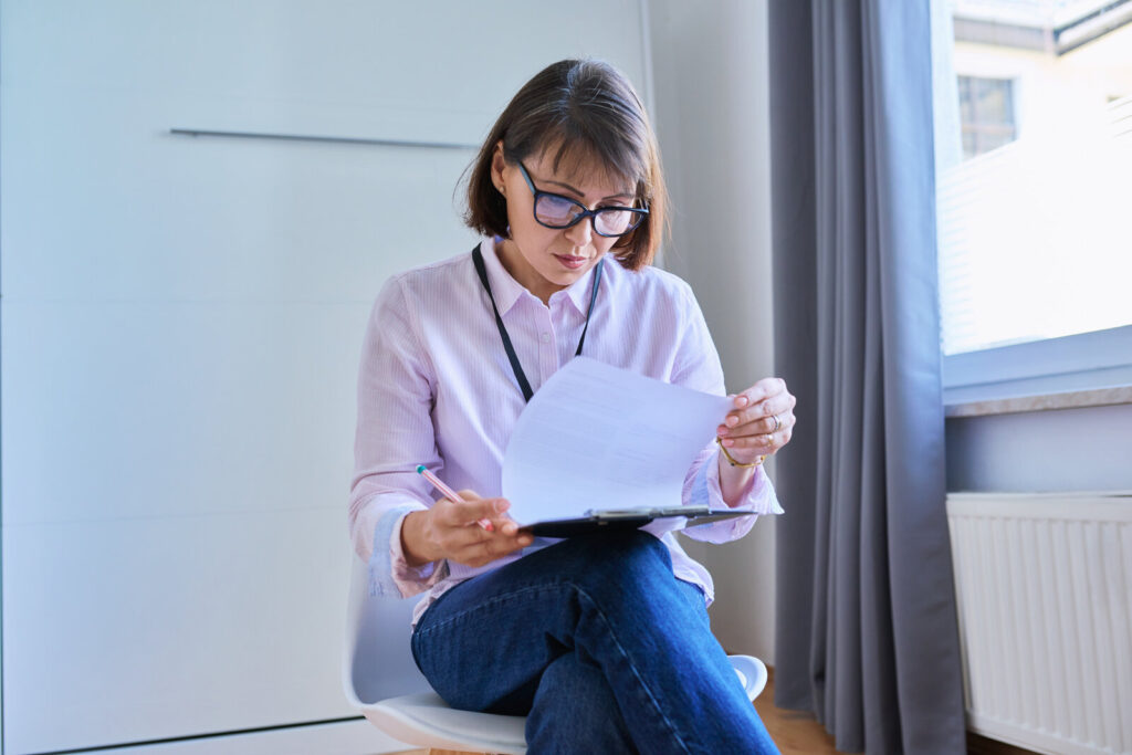 Woman at home reading a printed letter with medical test results