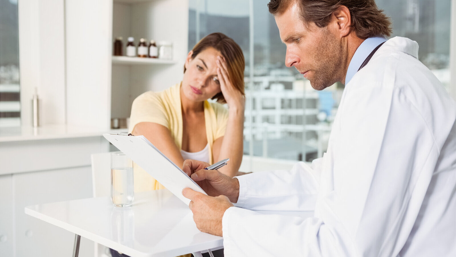 Worried woman sitting while a doctor reviews her test results